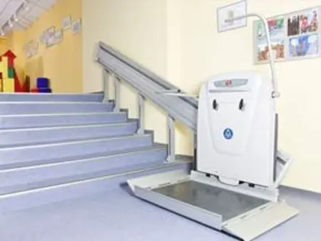 Wide shot of a stair lift at the base of grey stairs.
